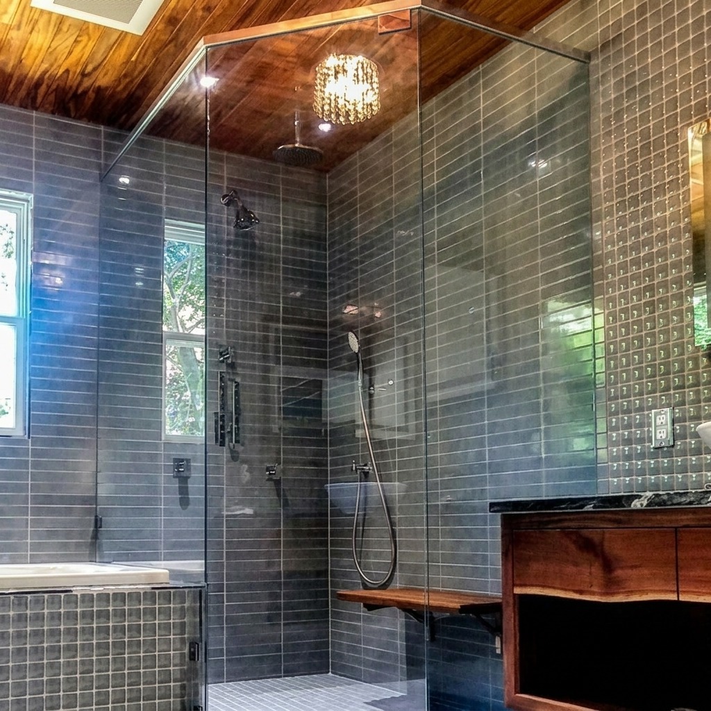 Frameless glass shower enclosure with dark grey tile under a wood plank ceiling, installed by Shower Doors of Dallas