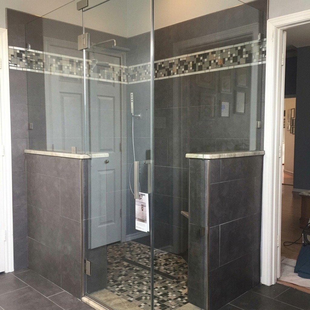 Frameless glass corner shower on knee walls with dark gray tile