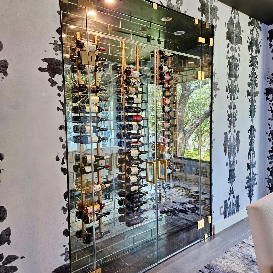 Frameless glass wine room with lit bottle racks and patterned wallpaper