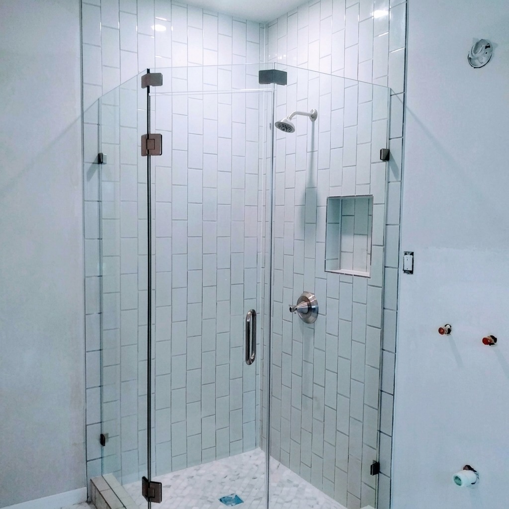 Neo-angle frameless glass shower with white tile and black hinges