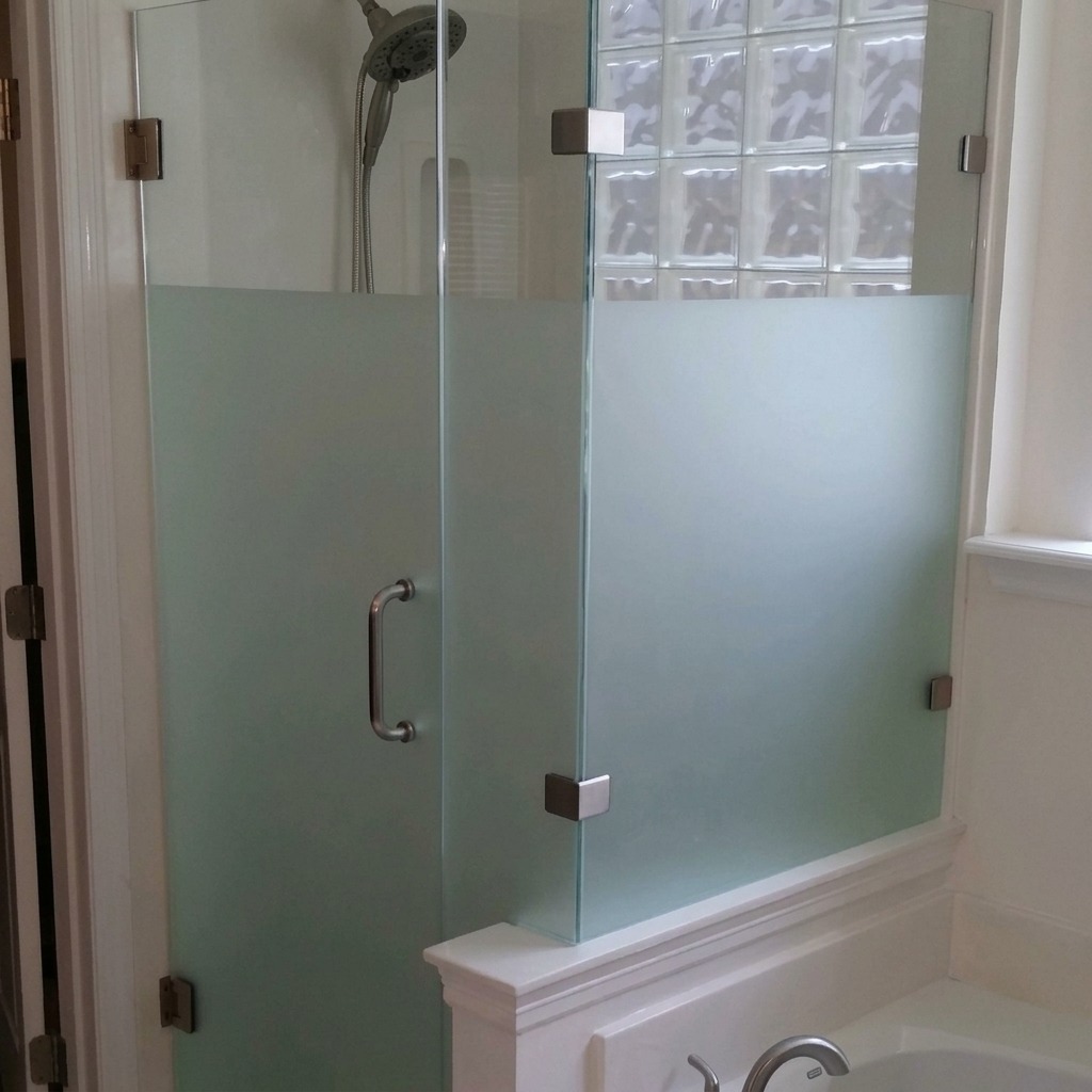 Frosted glass frameless shower door and panel on a tiled knee wall