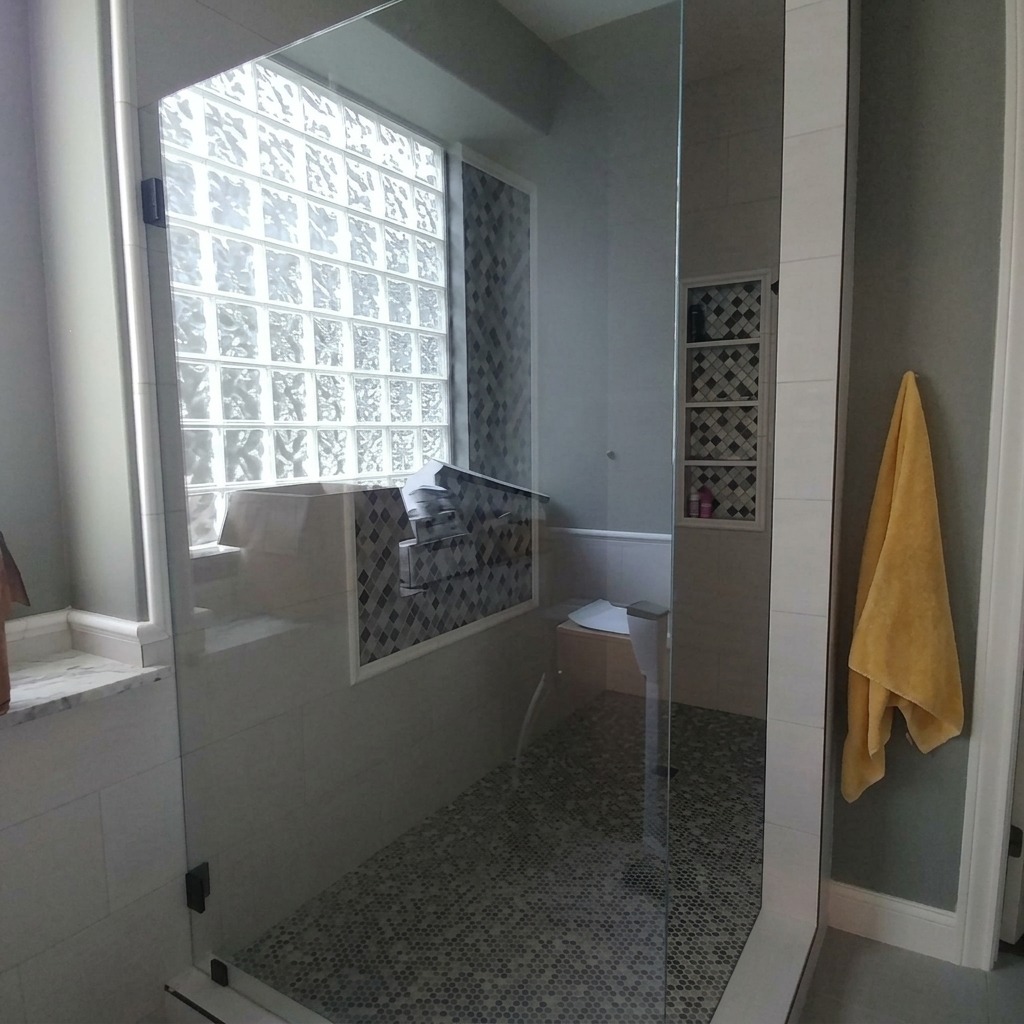 Frameless glass shower panel and door beside a glass block window