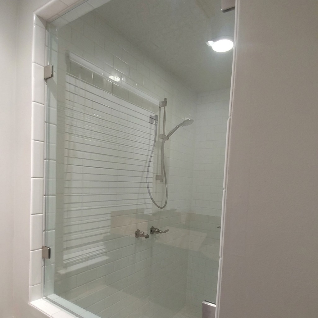 Custom cut frameless glass shower panel with a shaped edge