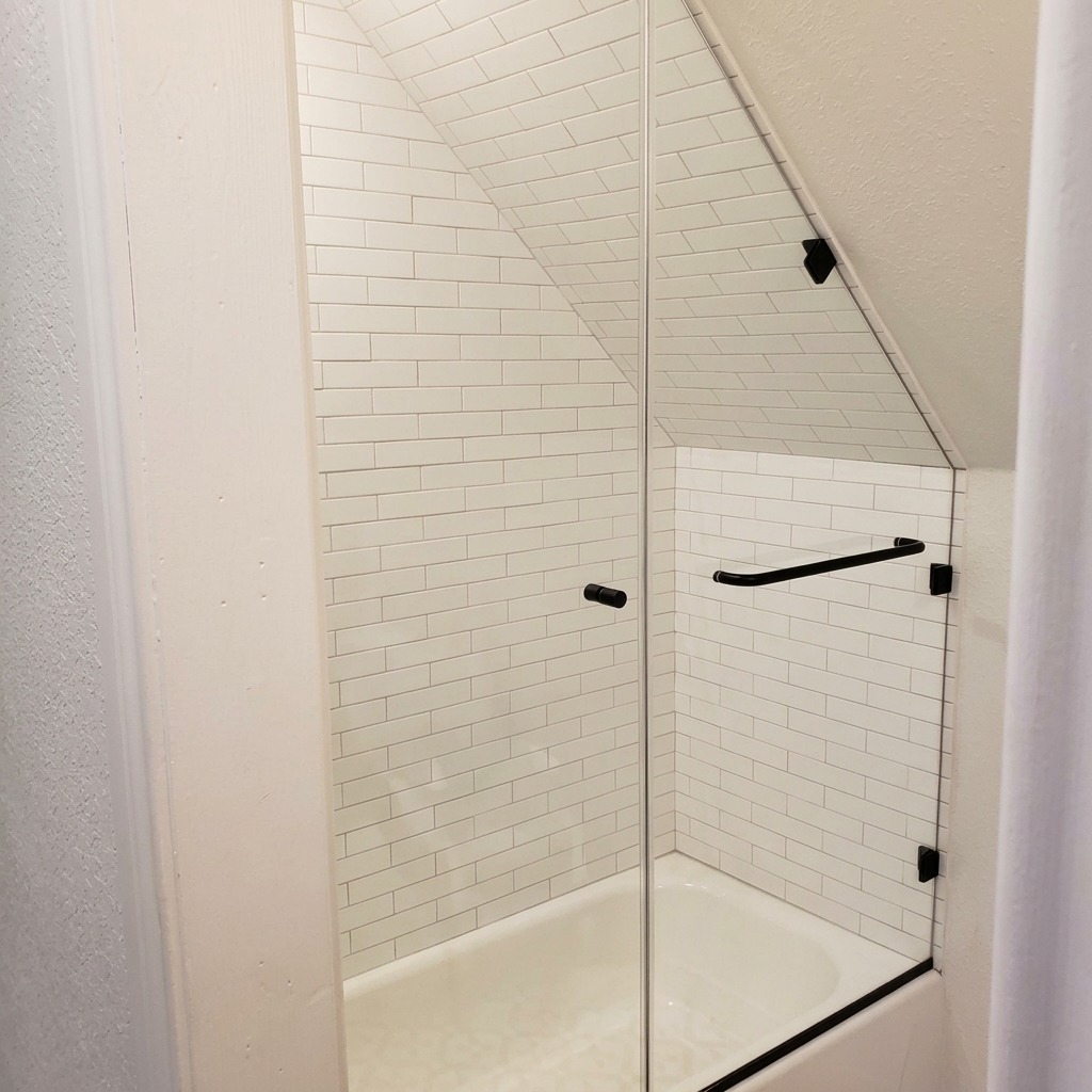 Raked Frameless Glass with Black Hardware (high resolution) Raked frameless shower glass with matte black hardware under a sloped ceiling