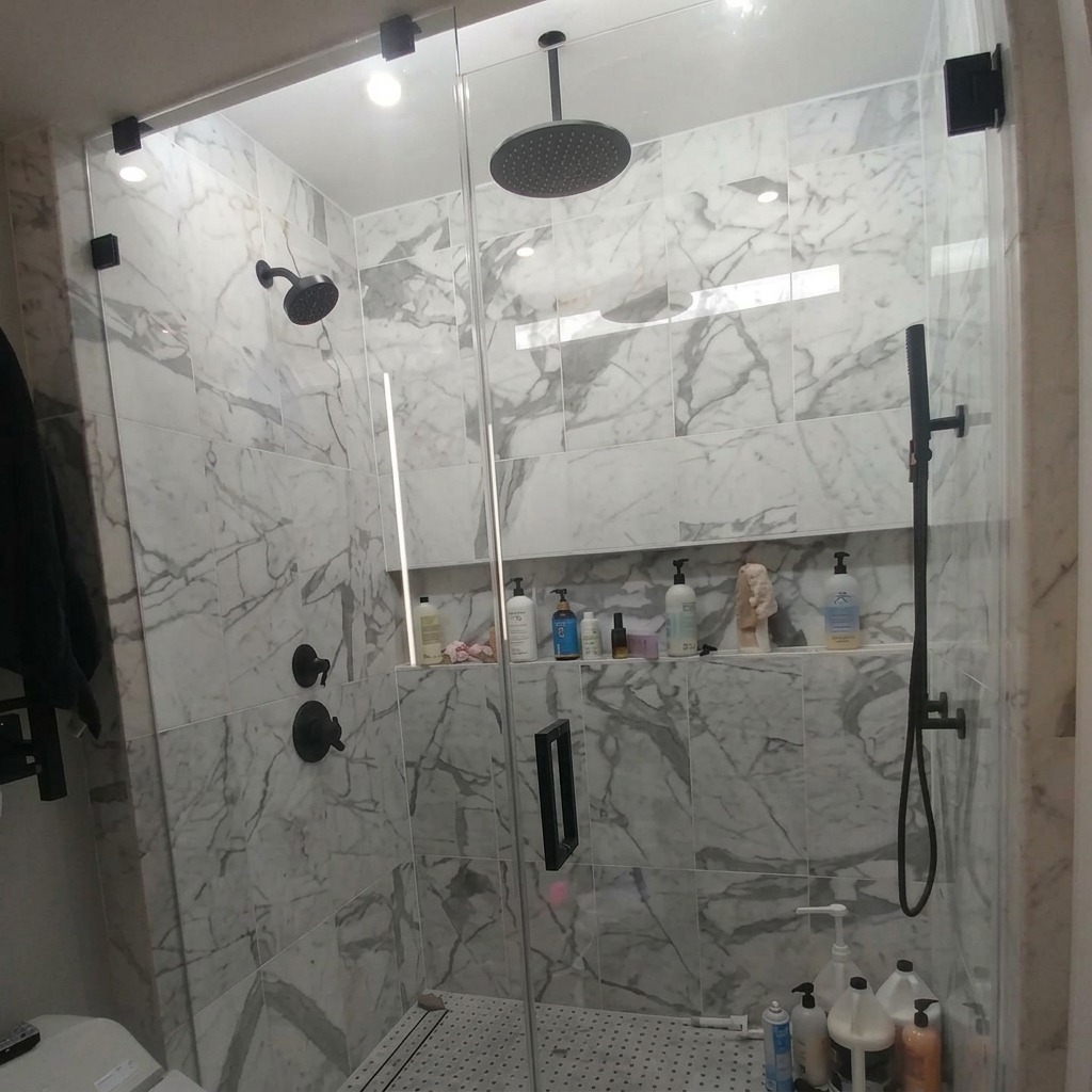 Full-height frameless steam shower glass with black hardware on marble tile