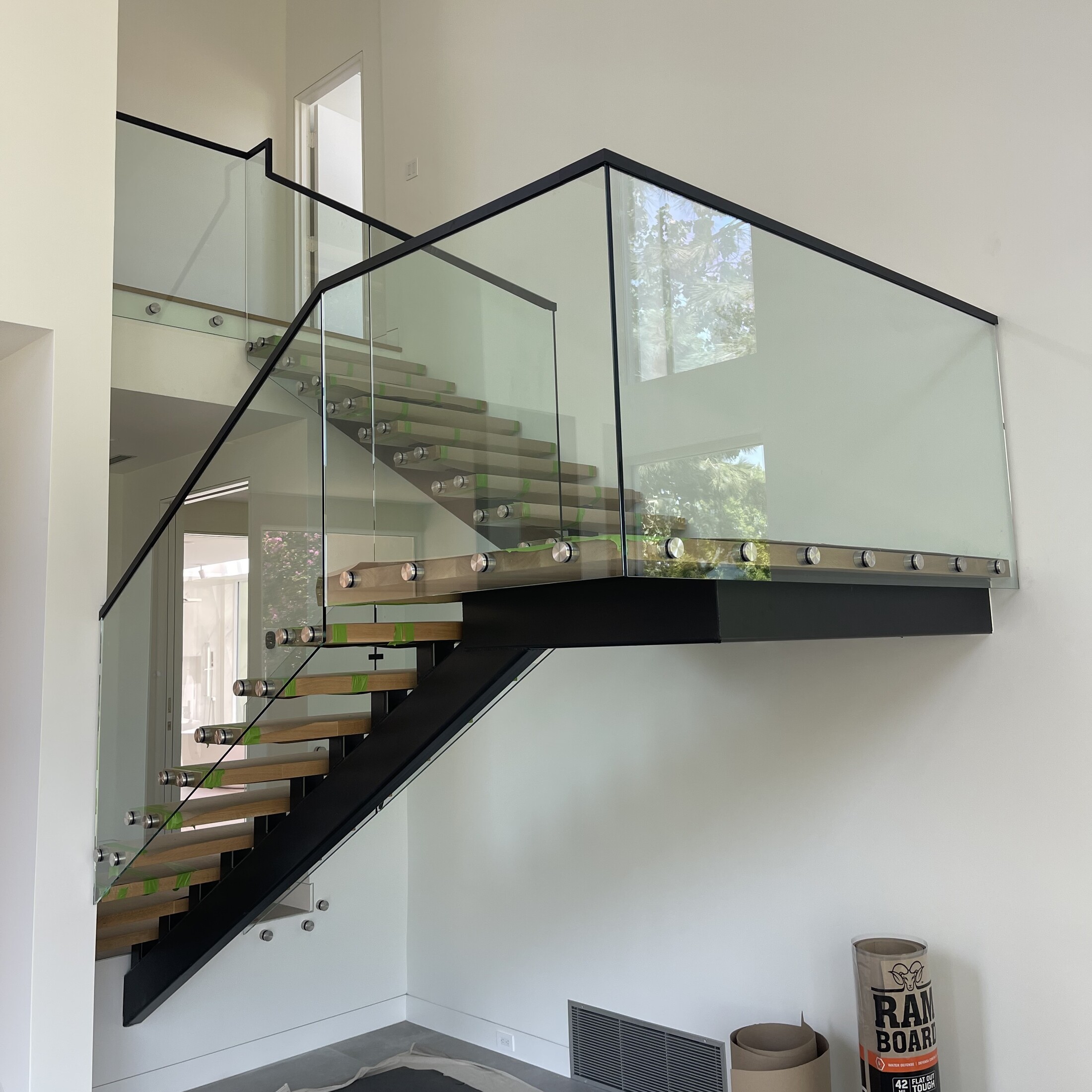 Frameless glass railing panels with standoff mounts on a floating wood-tread staircase