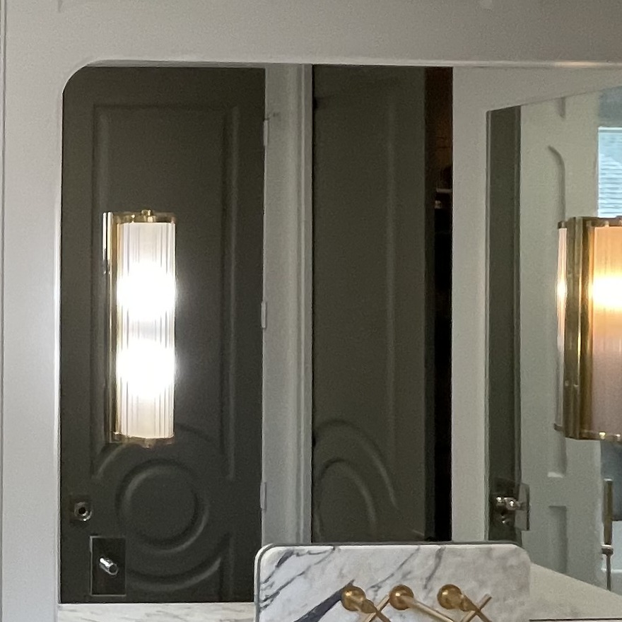 Frameless custom mirror with a radius corner above a marble vanity backsplash