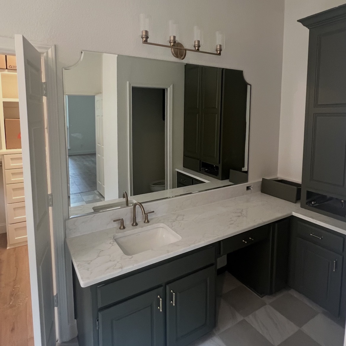 Custom vanity mirror with scalloped corners above a grey vanity and white countertop