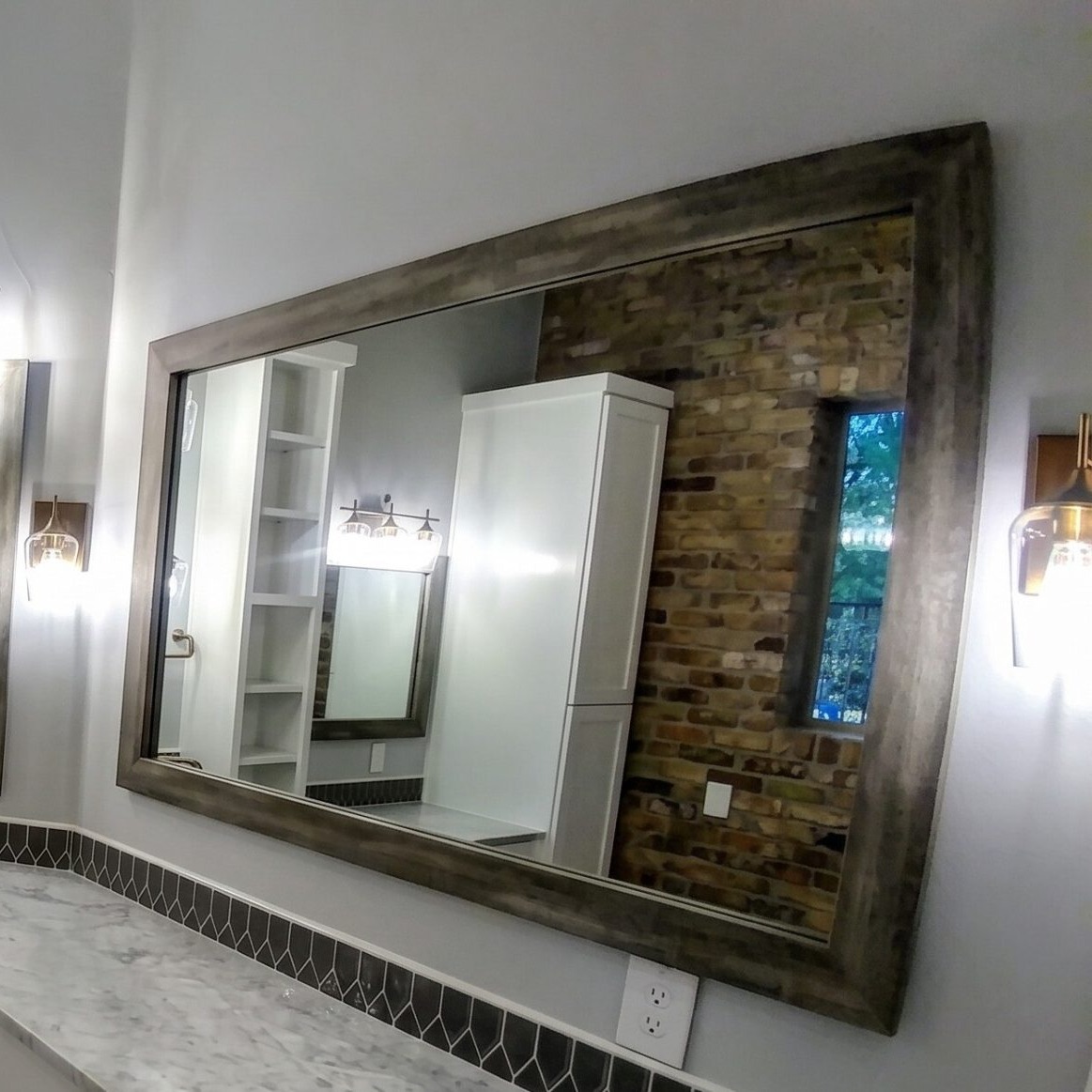 Large weathered wood framed custom mirror reflecting a brick accent wall