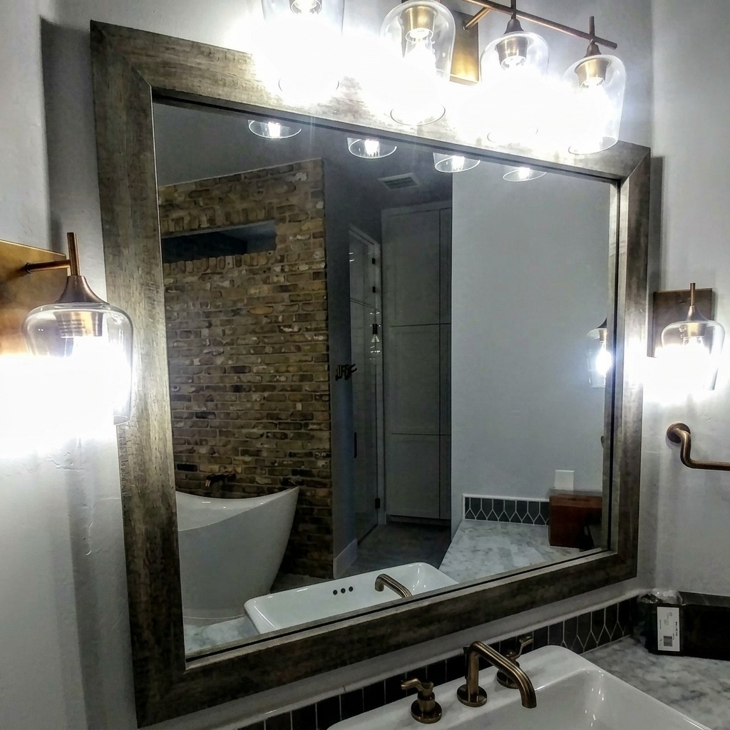 Framed custom vanity mirror under a glass pendant light bar above a vessel sink