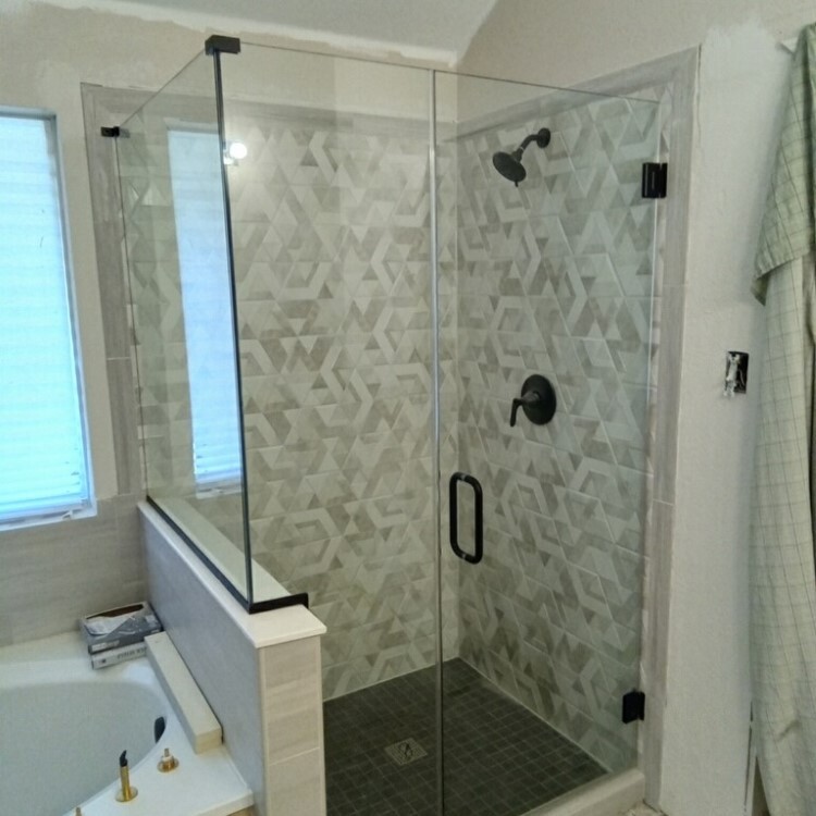 Frameless shower enclosure on a half wall with oil-rubbed bronze hardware