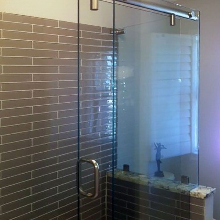 Frameless sliding glass shower door with a plank tile wall