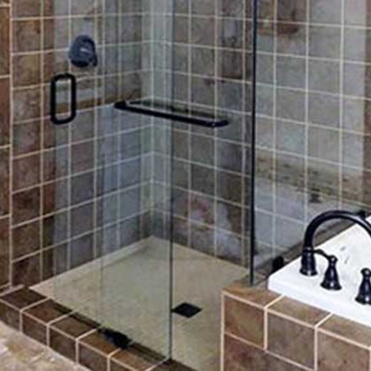 Frameless shower enclosure with a towel bar handle and brown tile