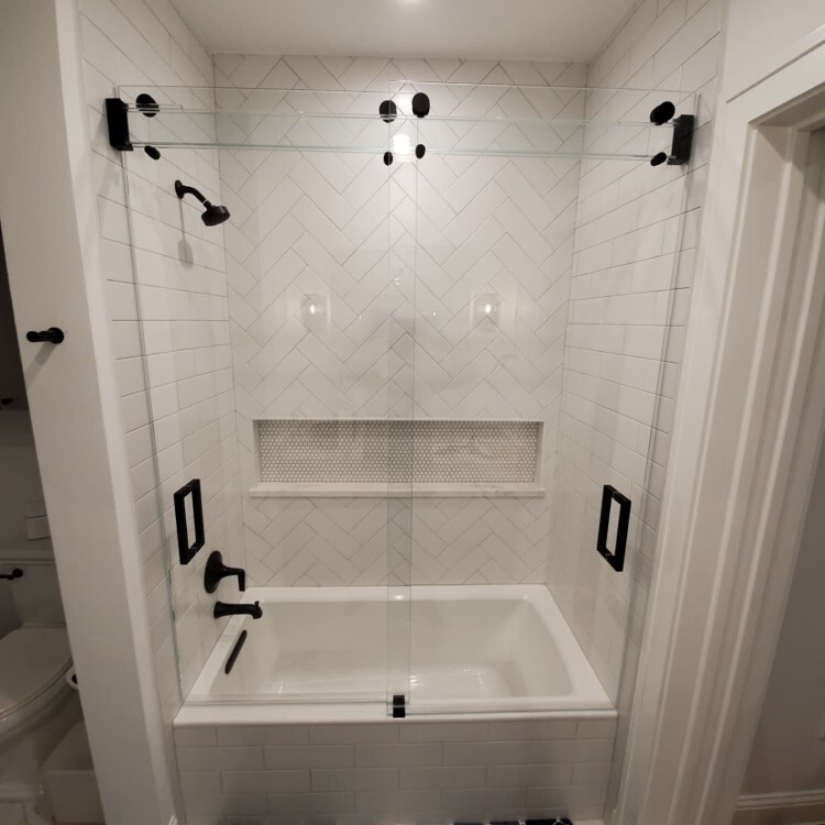 Nearly invisible frameless glass tub enclosure with matte black pulls