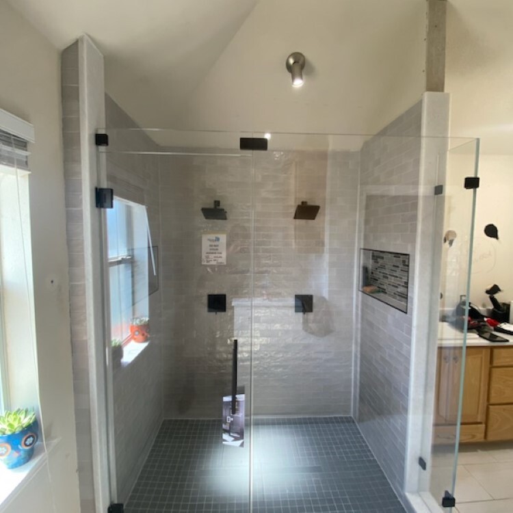 Frameless walk-in shower enclosure with matte black hardware and a window