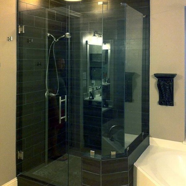 Neo-angle frameless shower enclosure with dark tile walls
