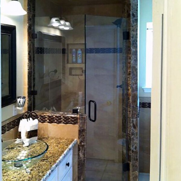 Neo-angle frameless shower enclosure beside a granite vanity with a vessel sink