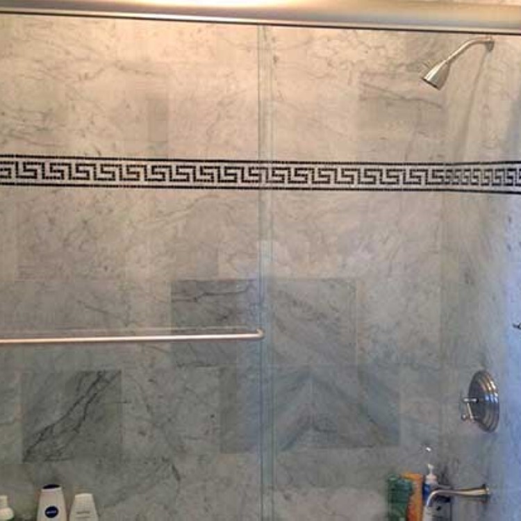 Sliding glass tub enclosure with marble tile and a Greek key border