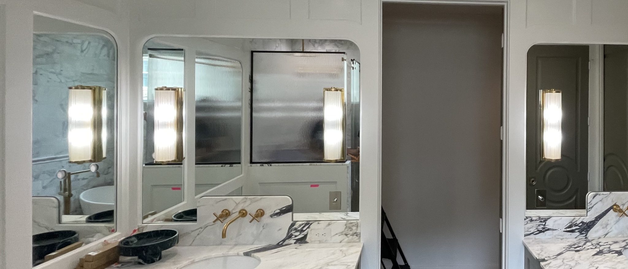 Custom radius-corner vanity mirrors with brass sconces above a marble double vanity