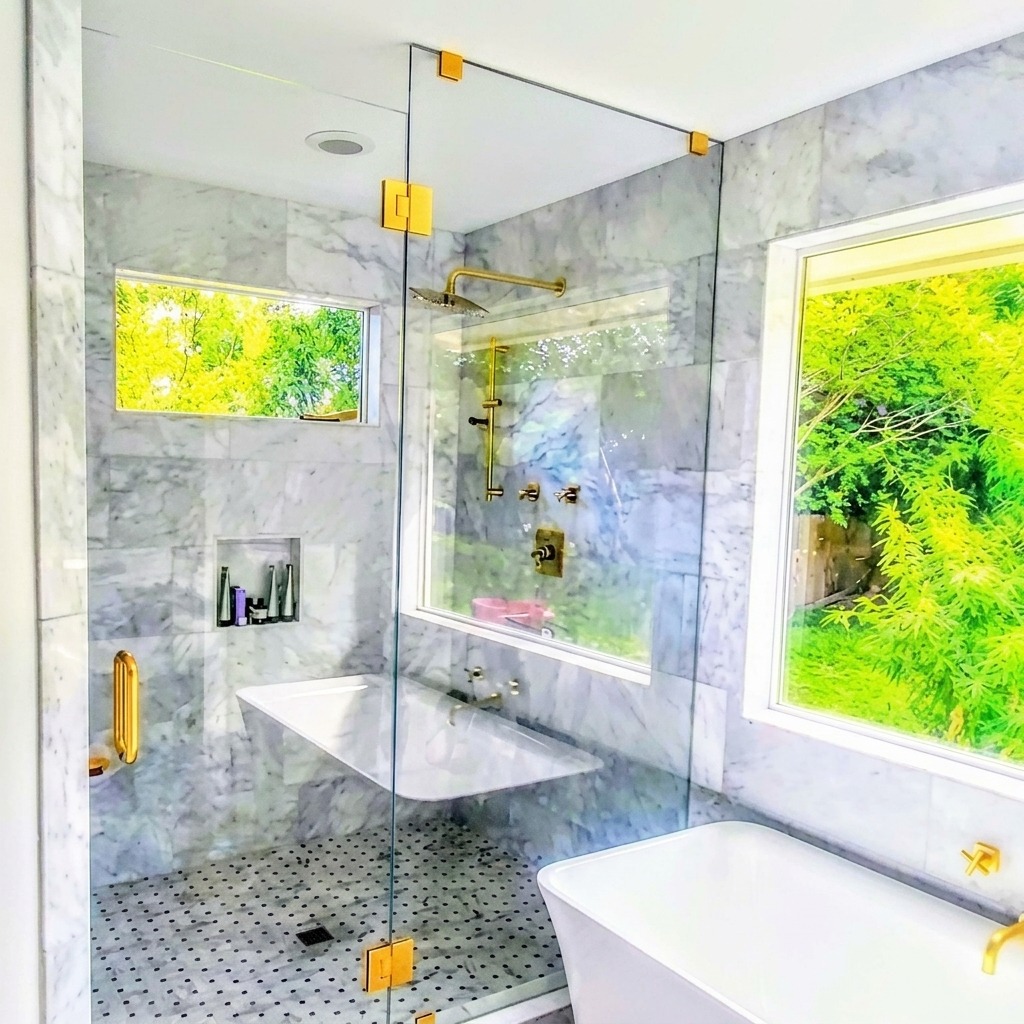 Frameless glass shower with brass clamps (high resolution) Frameless glass shower with brass clamps and hinges beside a freestanding tub