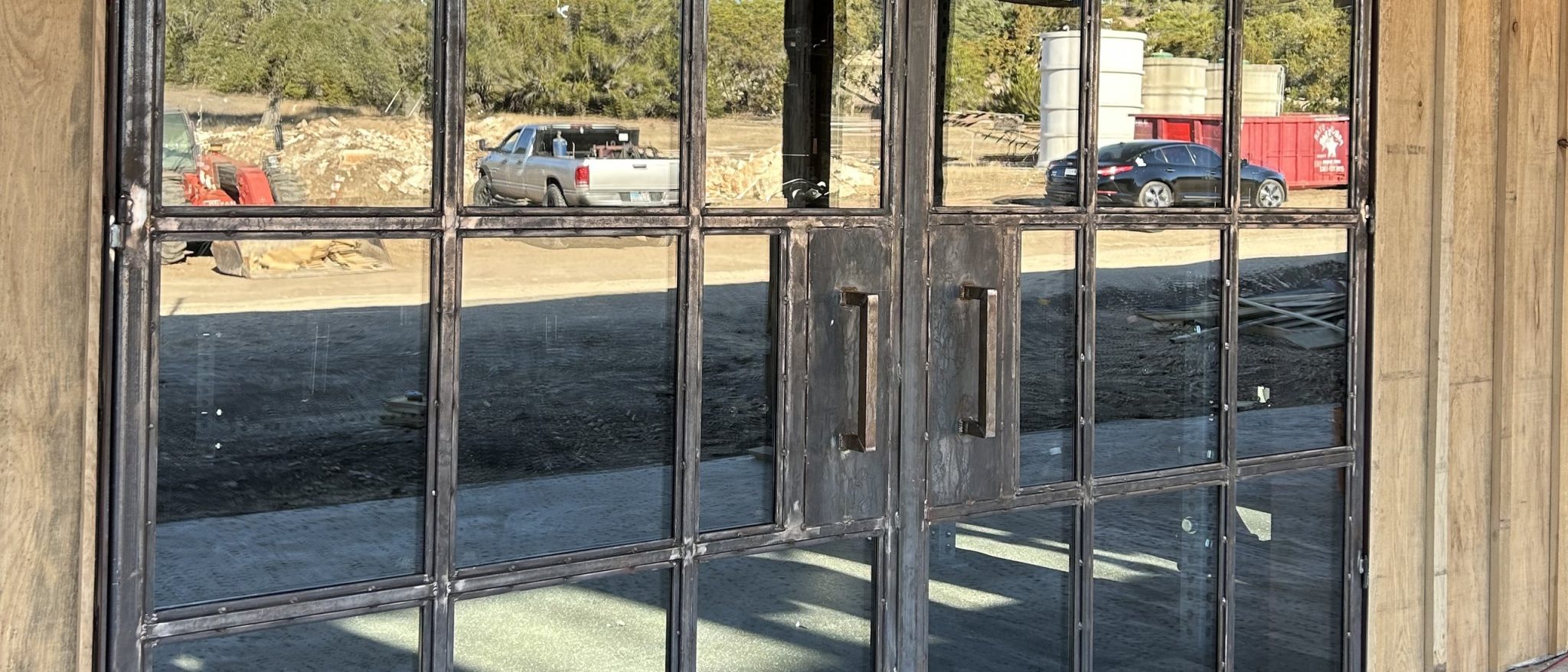 Steel grid glass double doors with long bar pulls set in a reclaimed wood wall