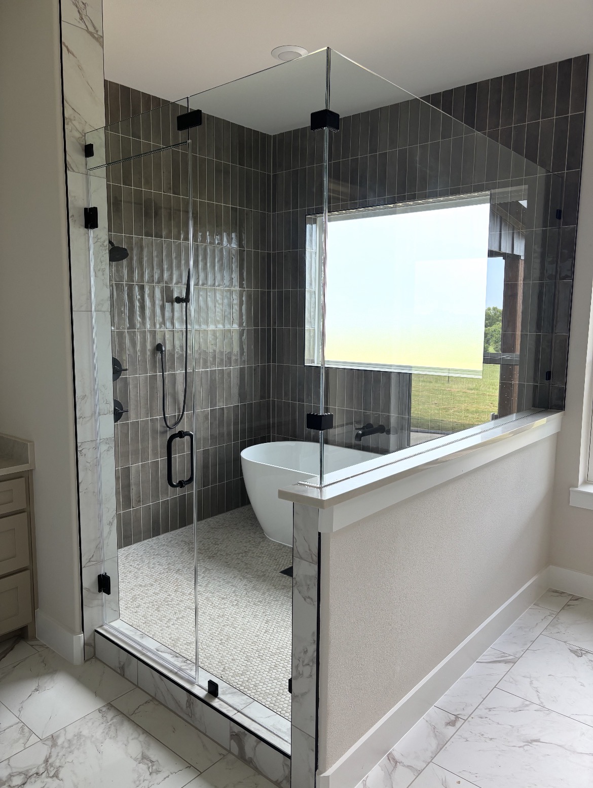 Frameless 90-degree glass shower enclosure with matte black hardware and a pony wall, installed by Shower Doors of Dallas