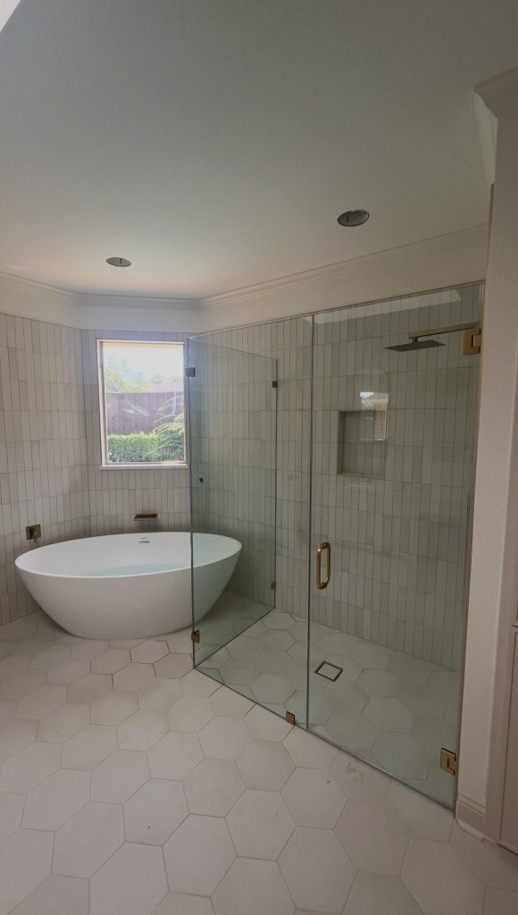 Frameless 90-degree glass shower enclosure beside a freestanding tub in Plano, TX