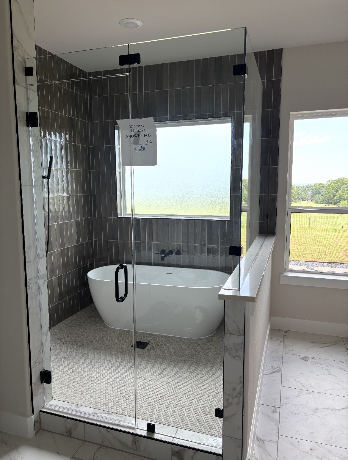 Second view of the frameless 90-degree enclosure with transom against dark grey tile in Farmersville, TX