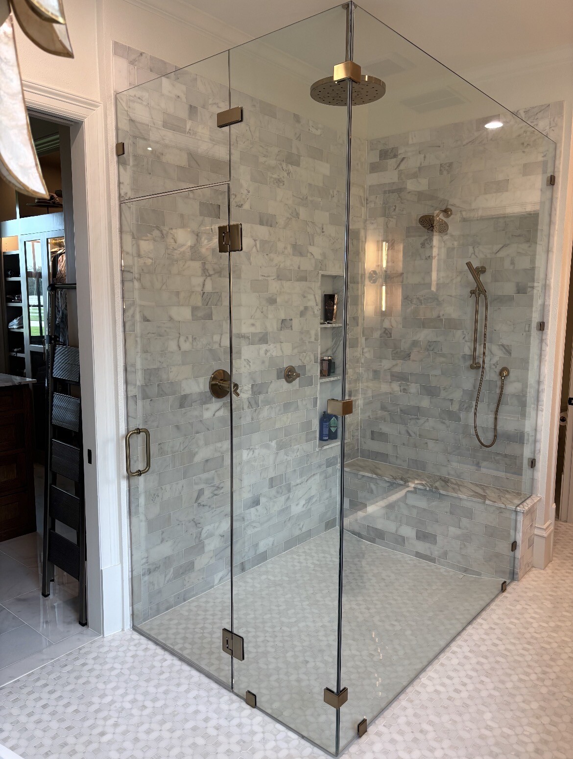 Frameless 90-degree shower enclosure with transom, custom notch and brushed bronze hardware in Bartonville, TX