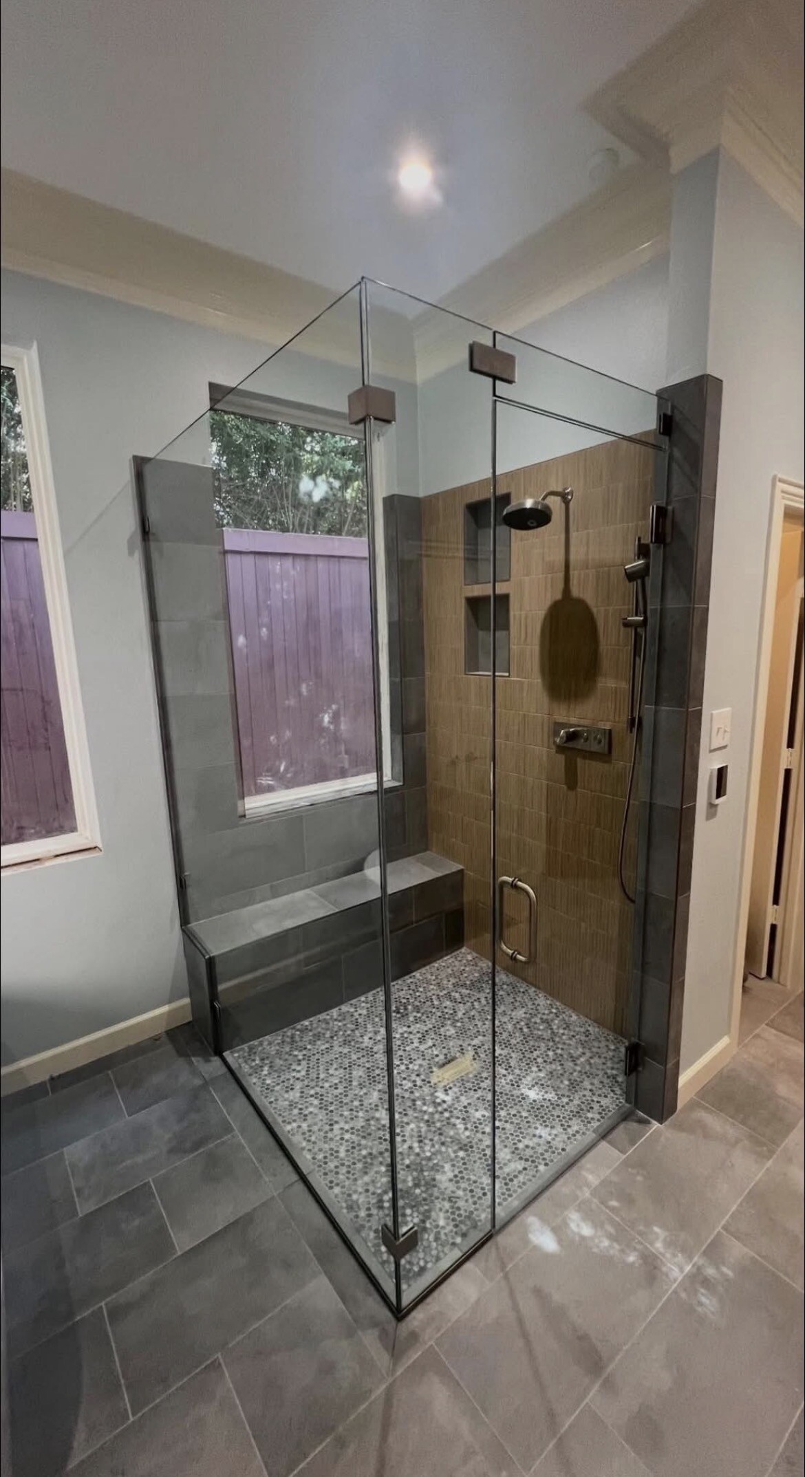 Frameless 90-degree shower enclosure with transom and dark tile interior in Frisco, TX