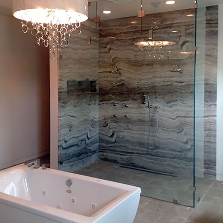 Frameless 90-degree glass shower enclosure beside a freestanding soaking tub