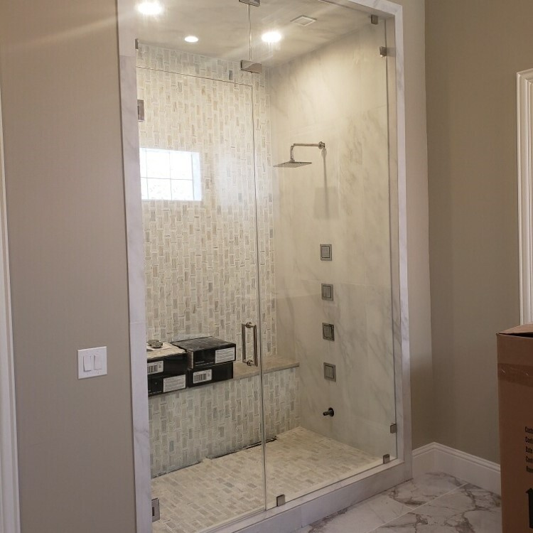 Frameless glass steam shower enclosure with a transom panel and white marble tile