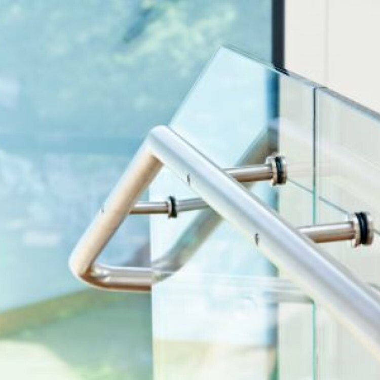 Glass stair railing with a brushed metal handrail on standoff brackets