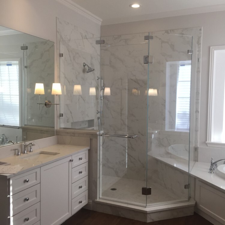 Neo-angle frameless shower enclosure next to a white double vanity