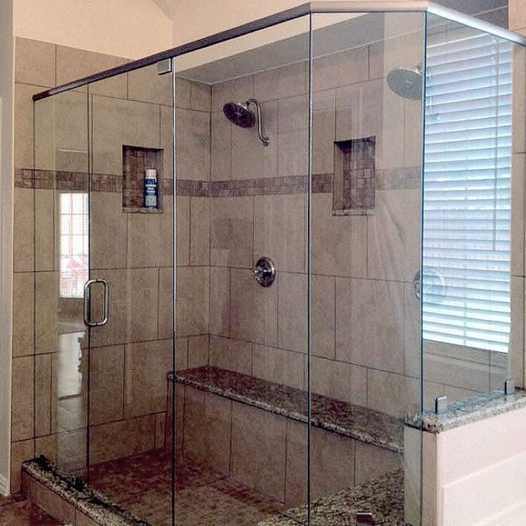 Neo-angle frameless shower enclosure with a granite bench and a tile accent band