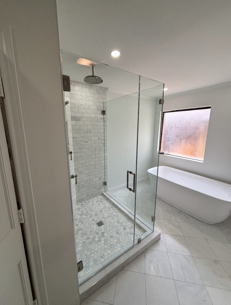 Frameless full 90-degree shower enclosure with polished nickel hinges and clamps beside a freestanding tub in Dallas, TX