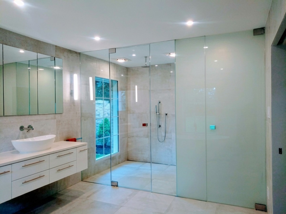 Floor-to-ceiling frameless glass shower wall with a frosted panel in a modern Dallas bathroom