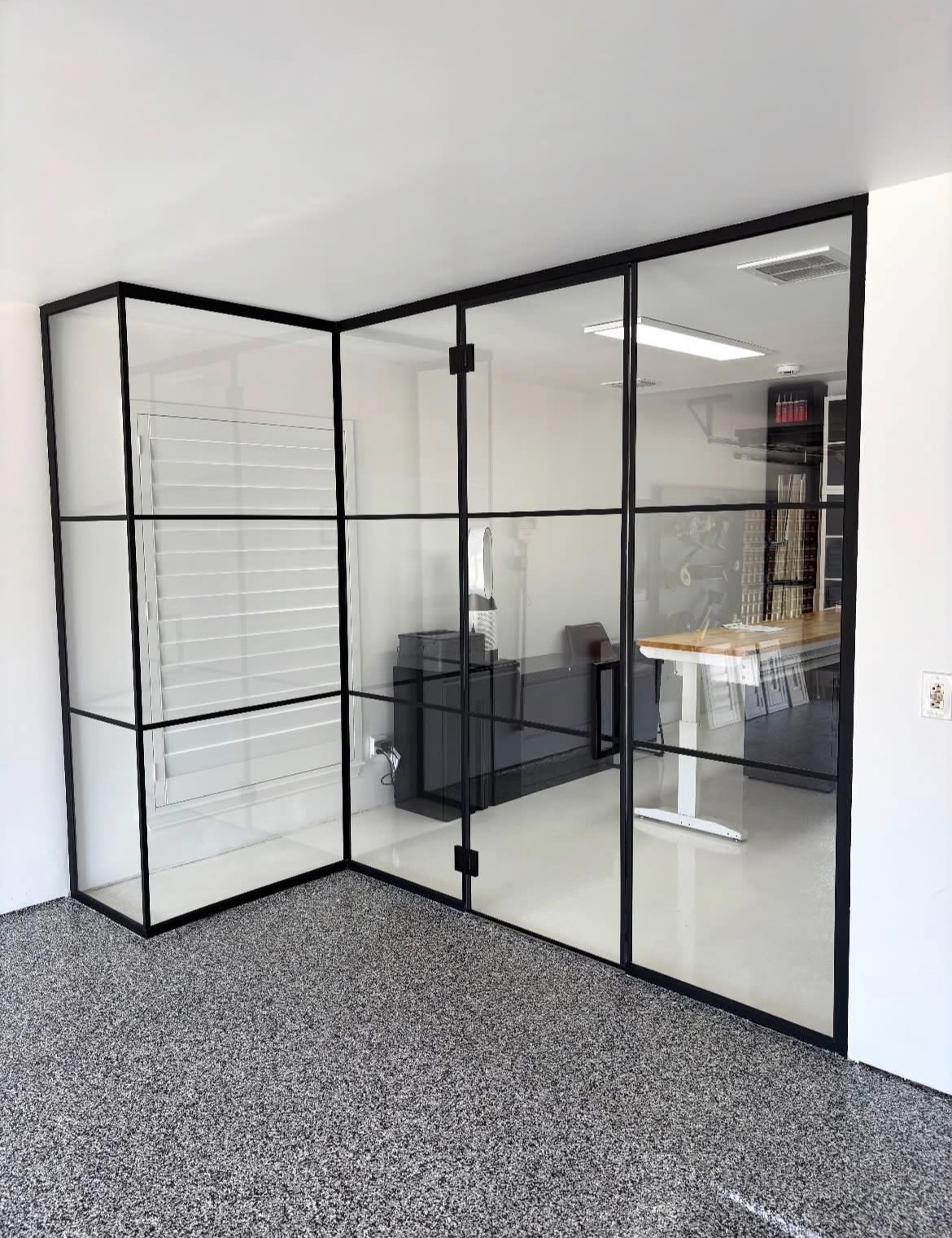 Floor-to-ceiling glass office partition with matte black Gridscape grid framing and a hinged glass door in McKinney, TX