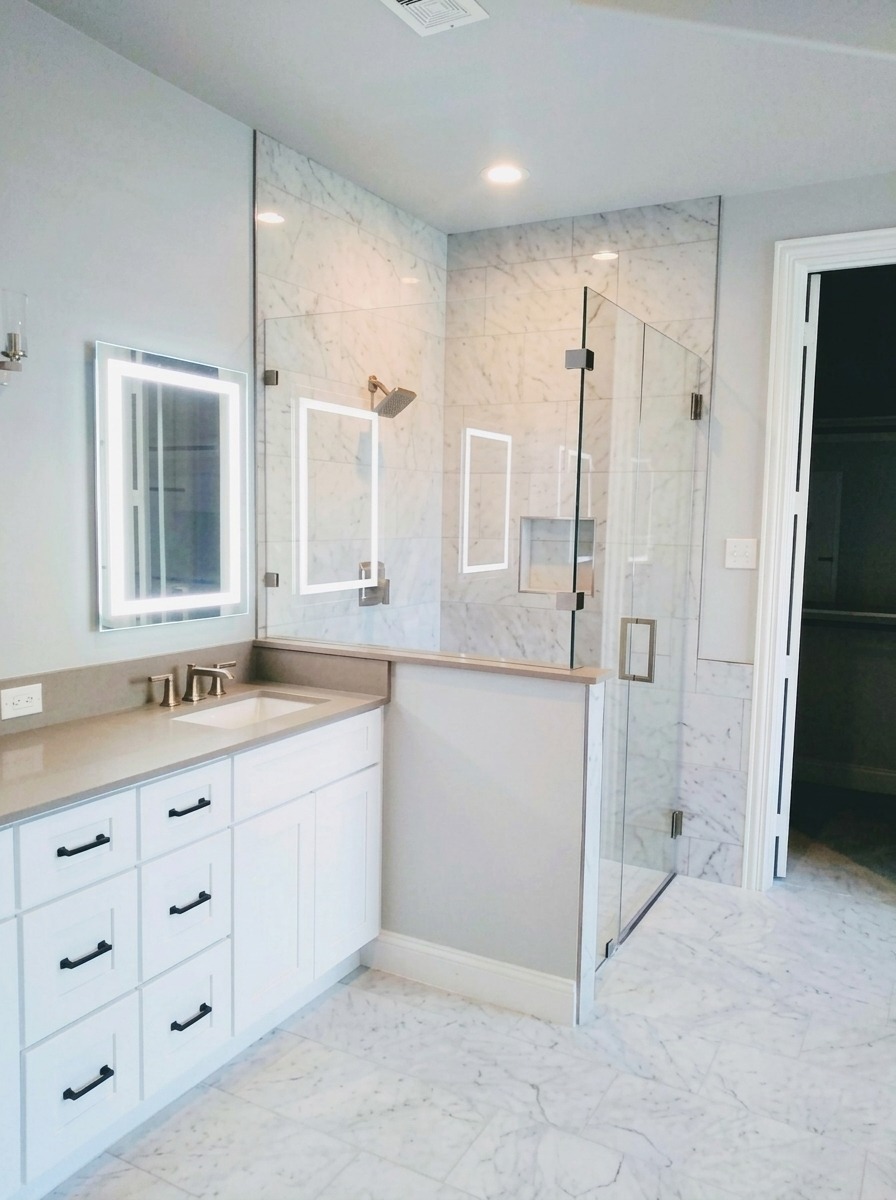 Frameless glass shower enclosure over a pony wall in a new-construction Dallas bathroom