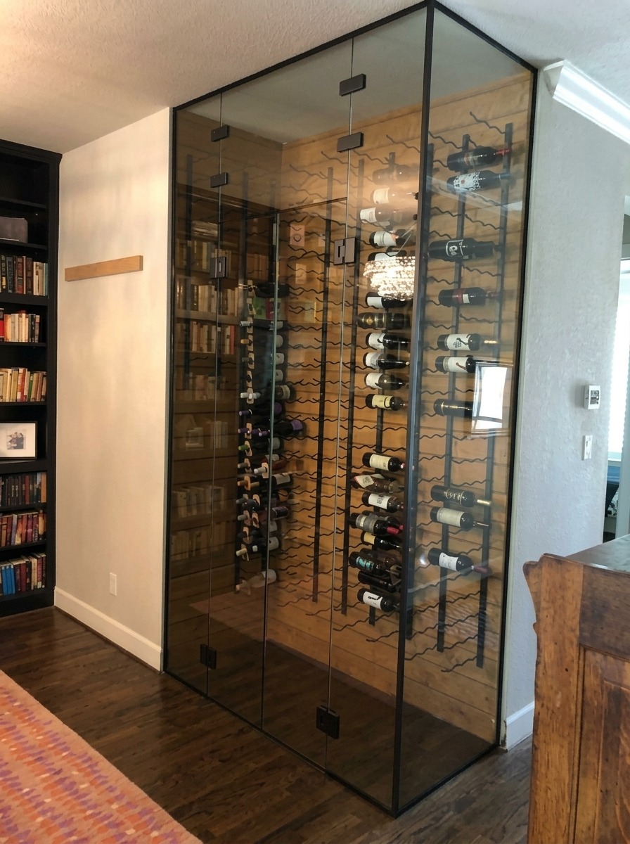 Floor-to-ceiling glass wine room enclosure with black frame details in a Dallas home