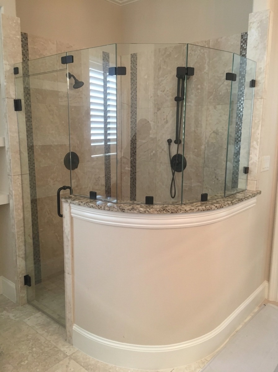 Frameless glass shower enclosure on a curved half wall with black hardware in a Dallas home