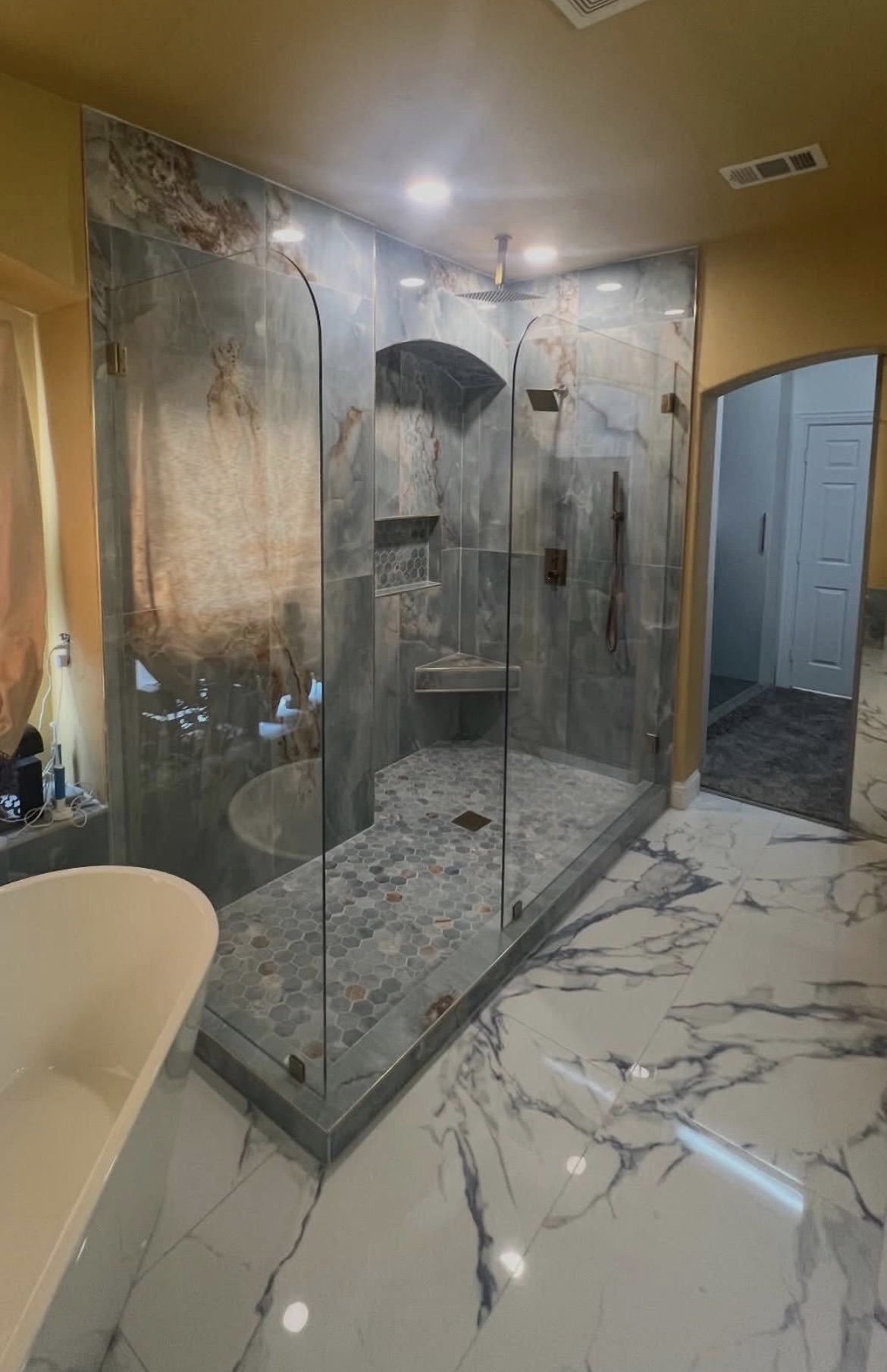 Frameless corner shower enclosure with two radius-corner splash panels beside a freestanding tub in a Dallas bathroom